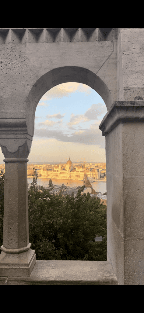 Budapest parliament with the sunsetting on it, framed by the Fisherman's Bastion arches. 