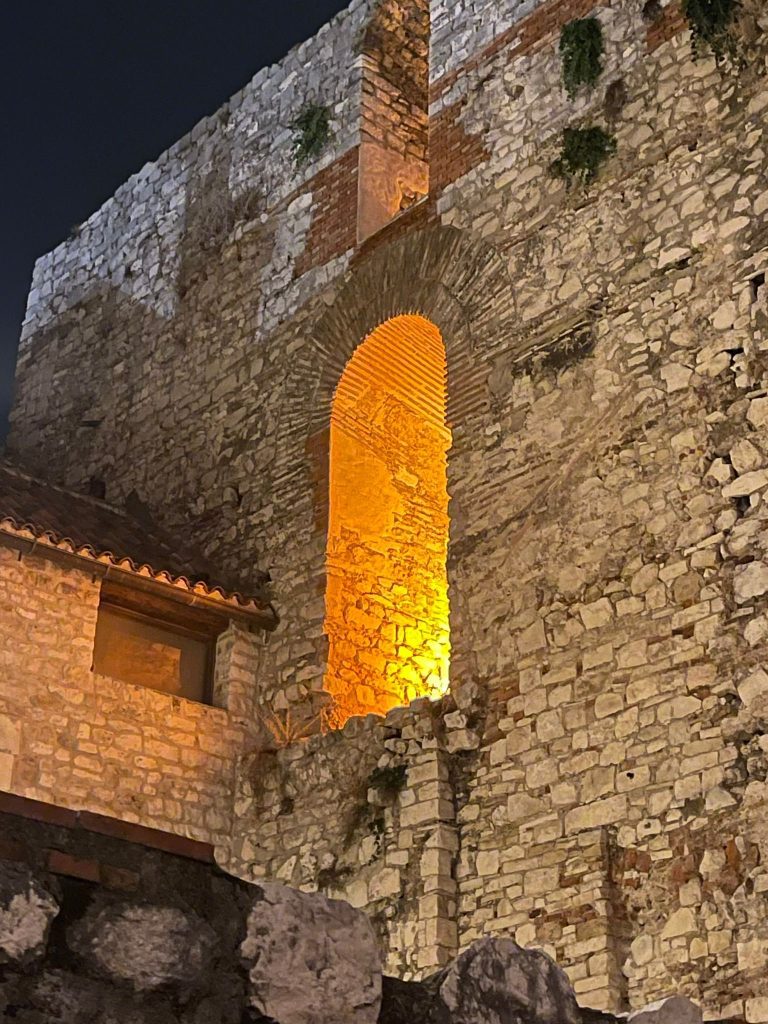 A Mediterranean style picture with cobbled walls and an arch with little beeping through it in split, Croatia. 