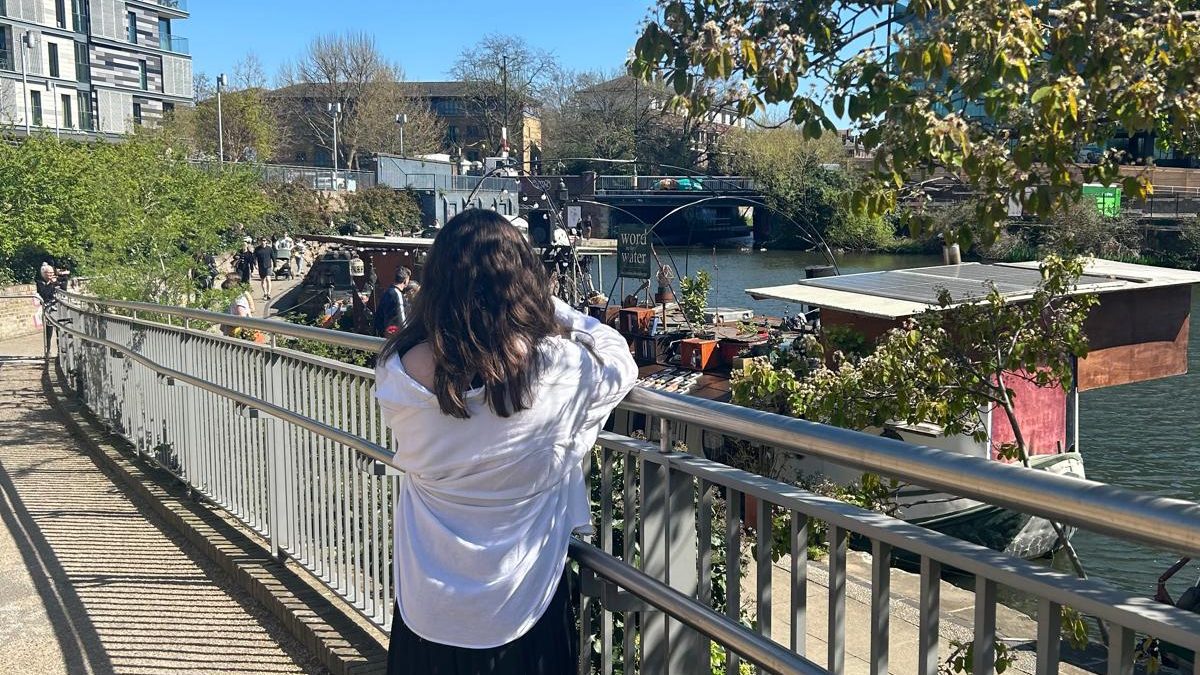 Back of girl taking a picture of the bookshop 'The Word on the Water' on a London Canal.