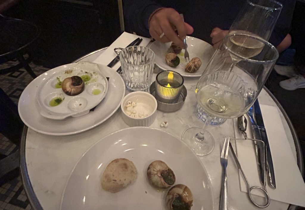 Two people trying Escargot in a restaurant in Paris.  