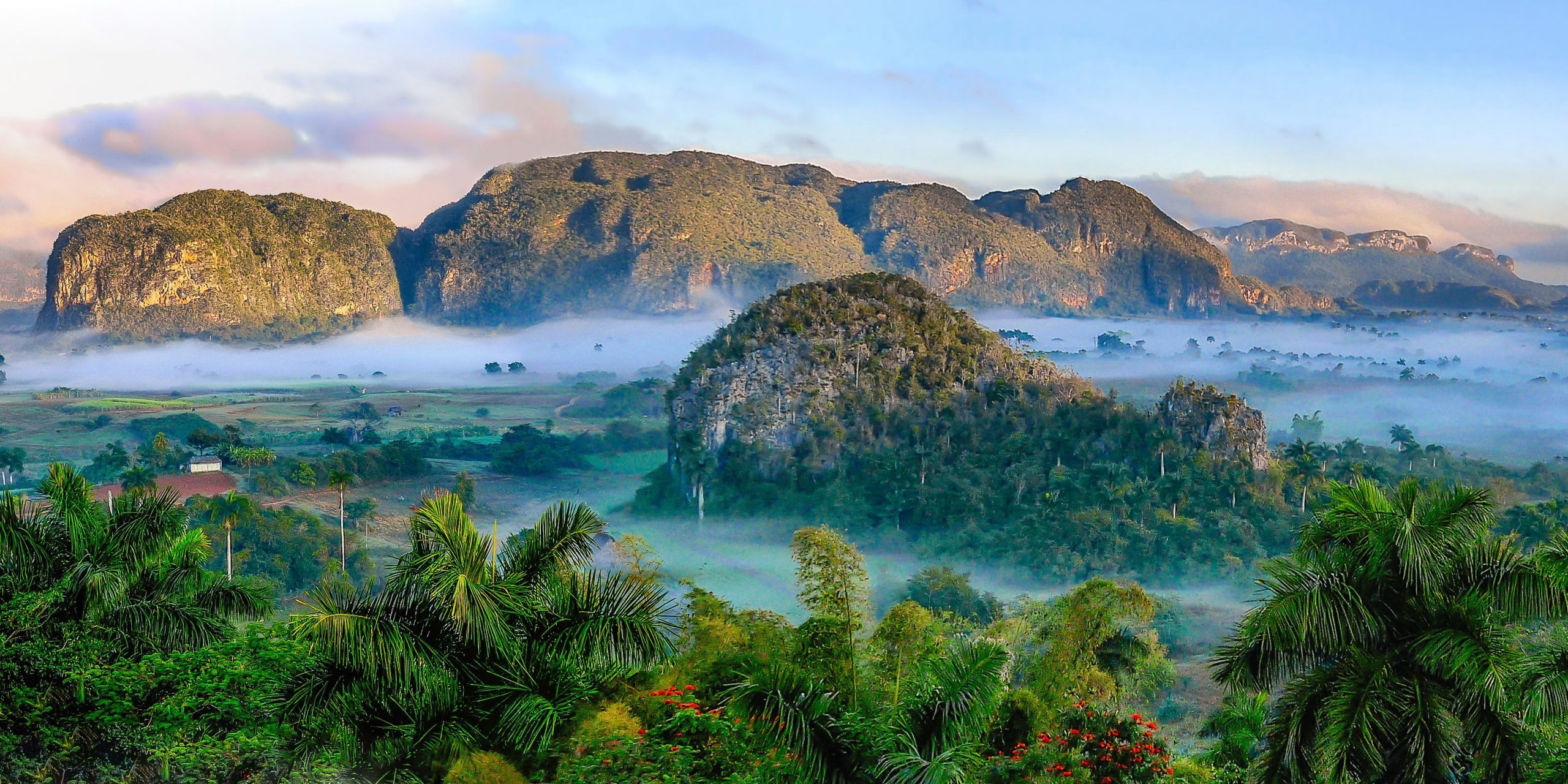 Mountains with green vegetation and African houses under foggy sky